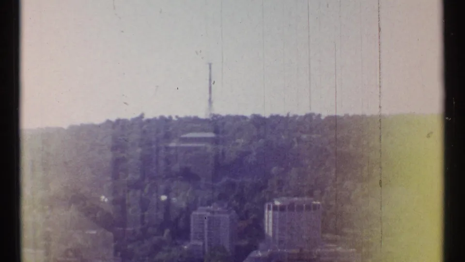 1967 Ottawa home-movie frame showing a communications tower over a wooded hillside with mid-century buildings below.