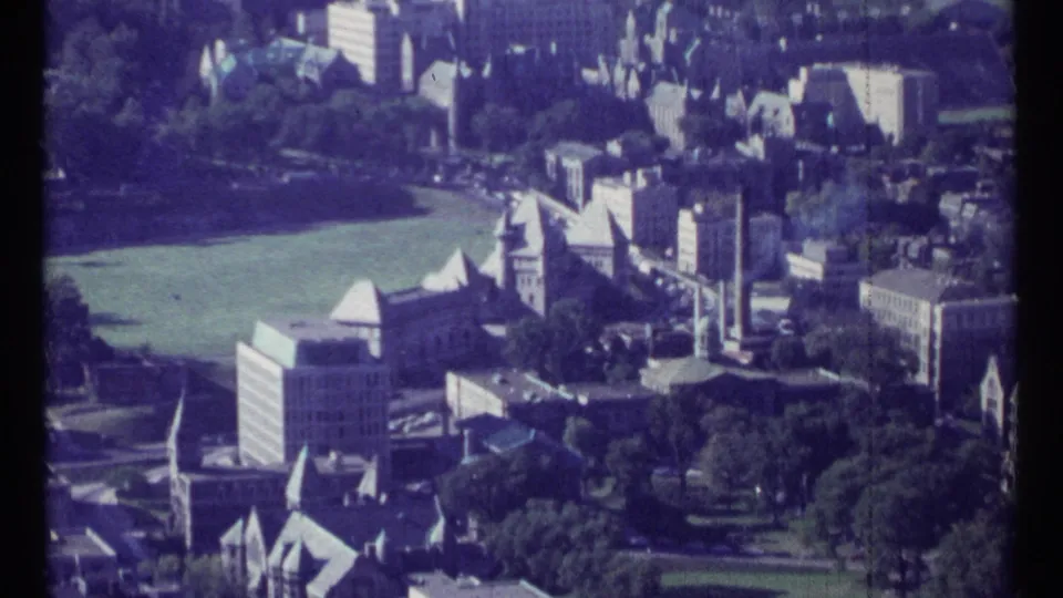 1967 Ottawa aerial view showing a green field, institutional buildings, older rooflines, trees, and streets with visible film grain and edge wear.
