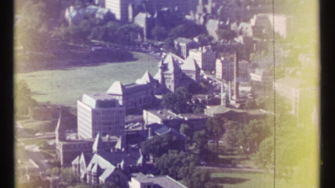 Aerial view of city buildings beside a green field with yellow film fading at the edge.