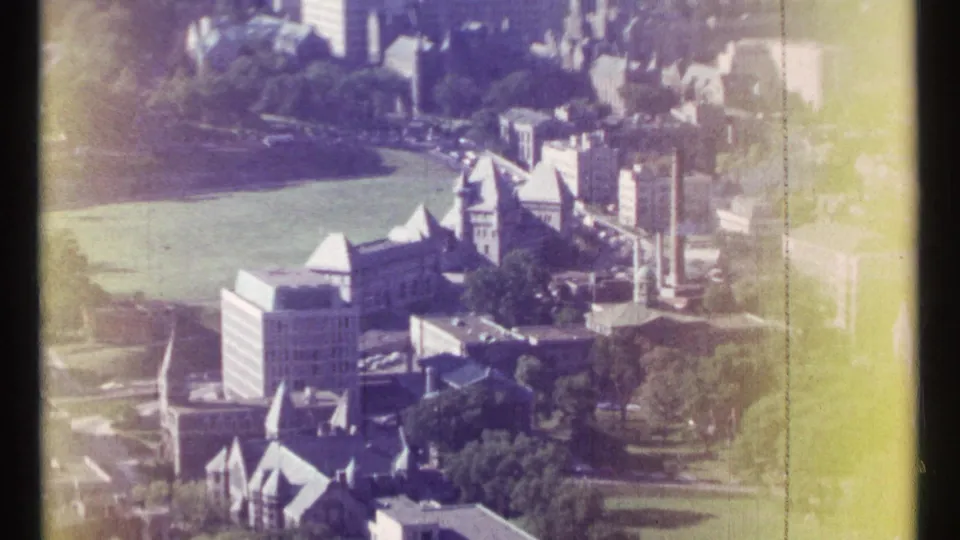 1967 Ottawa aerial frame with civic-looking buildings, a large green field, trees, streets, and yellow-purple color fading from the 8mm scan.