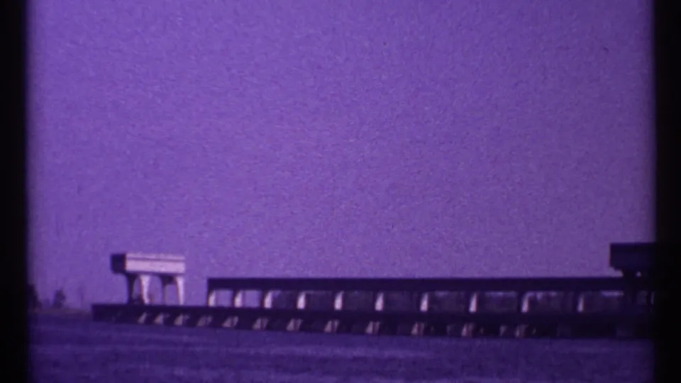 Final 1967 Toronto frame showing the low waterfront structure continuing across calm water beneath a purple-tinted sky.