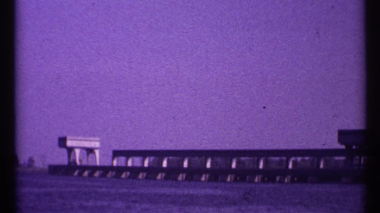 Long concrete span with repeating bays beside a waterway.