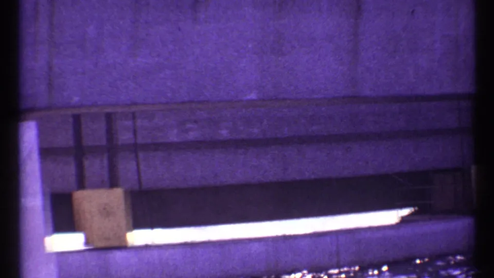 1967 Toronto 8mm frame showing a concrete wall or beam over reflective water, with a small rectangular panel near the span.