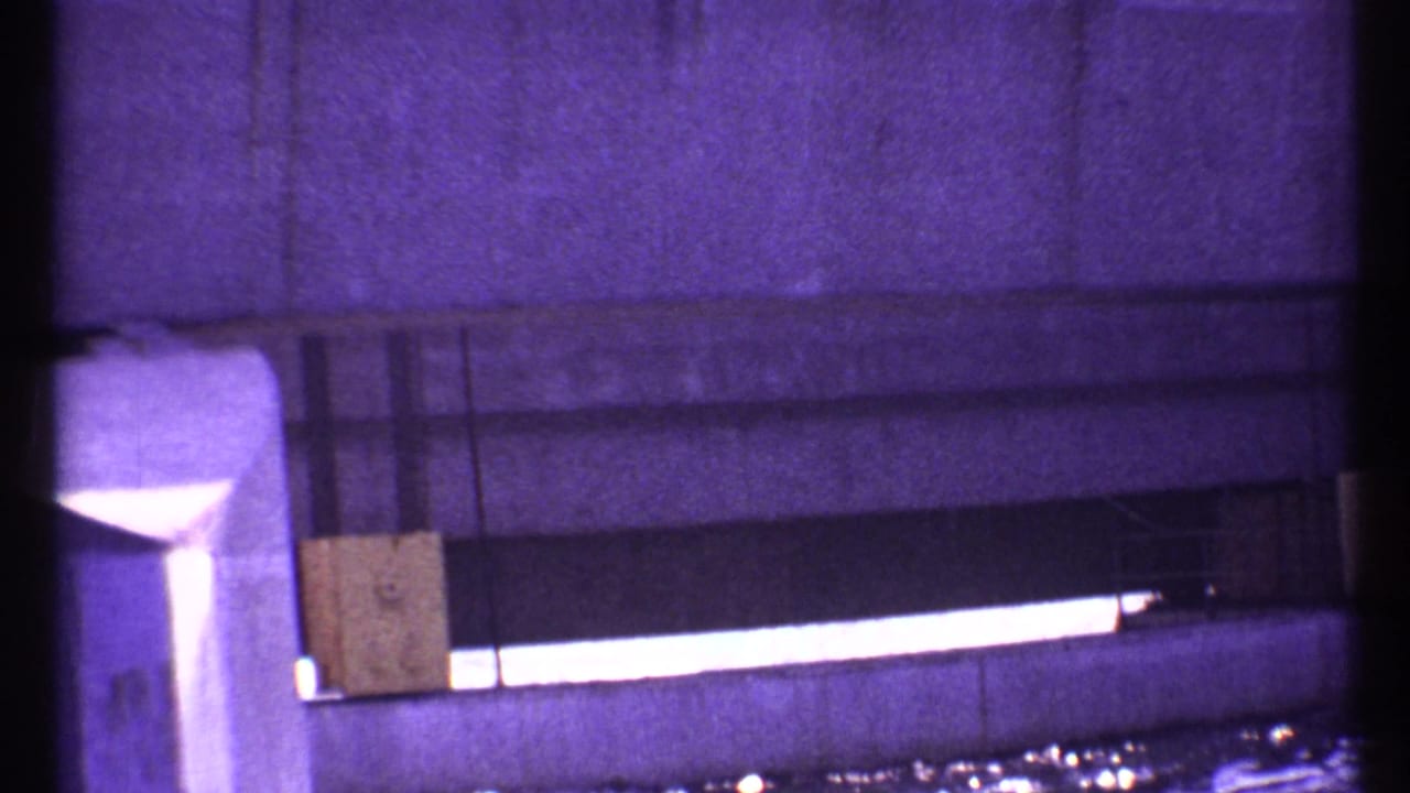 Close view of a concrete wall with a bright horizontal opening and dark film borders.