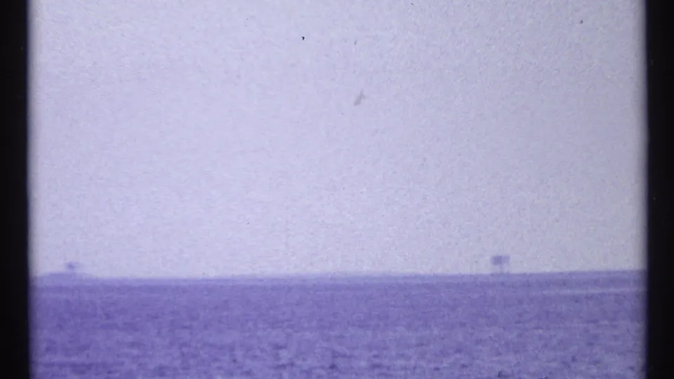 1967 Toronto-area 8mm frame showing open lake water, a pale hazy sky, and faint trees along the far shoreline.