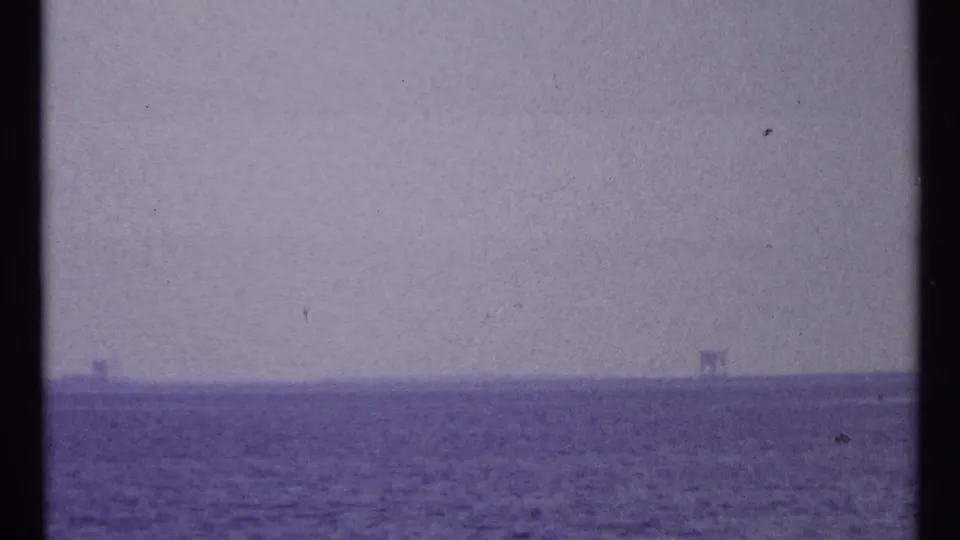 Purple-tinted 8mm view of open water near Toronto, with faint horizon structures and film gate edges visible.