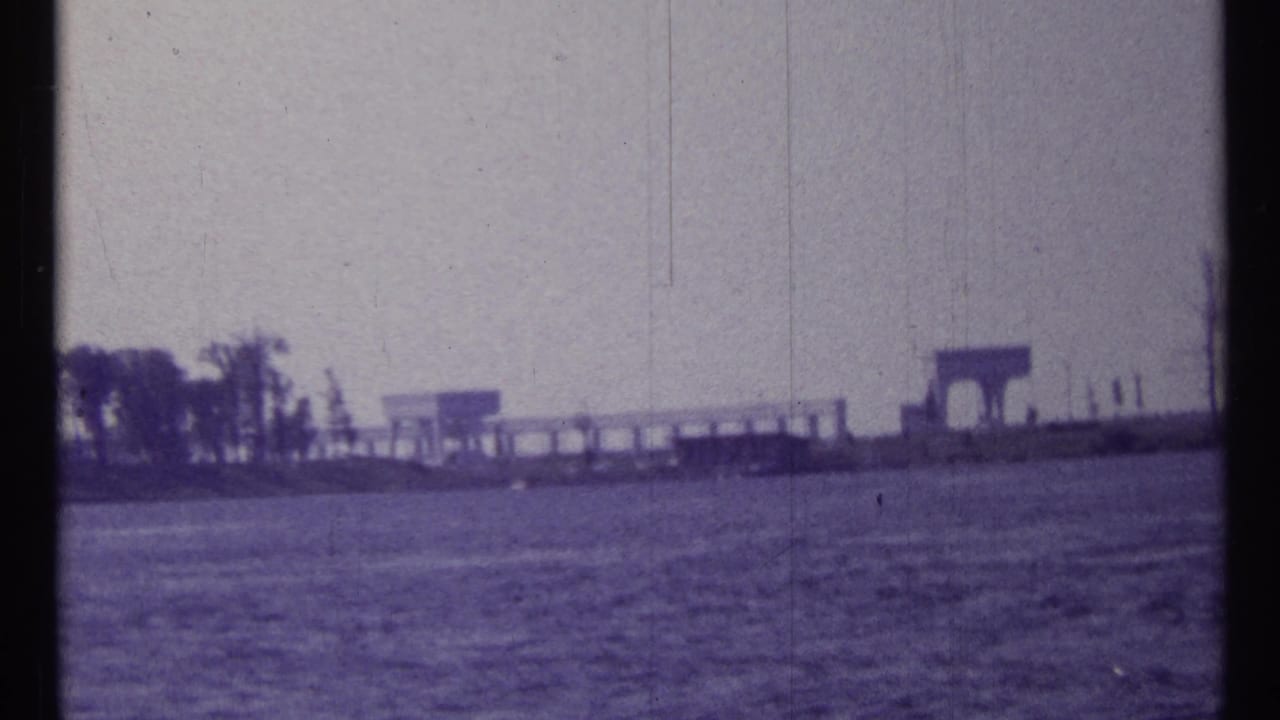 Open water with a distant shoreline and small waterfront structures near the horizon.