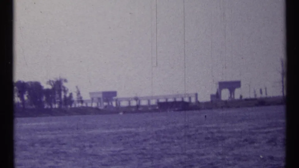 Boat-level 8mm view of water and a distant developed shoreline, consistent with the 1967 Toronto travel footage metadata.