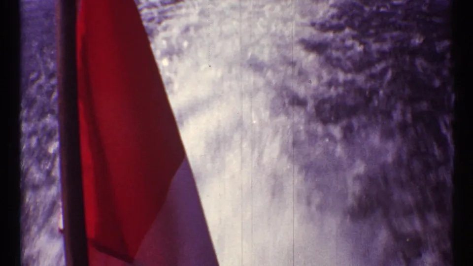 Red-and-white Canadian flag seen close up in 1967 Toronto 8mm footage, with soft focus, purple color shift, and visible grain.