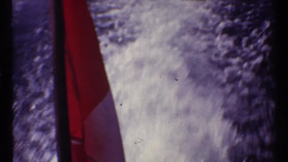 Close 8mm view of a Canadian flag at the Toronto waterfront, with purple-tinted grain and a dark vertical border in frame.