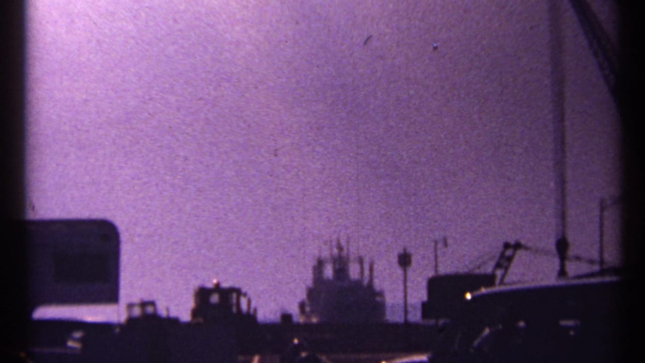 Dark ship and dock structures silhouetted against a purple sky.