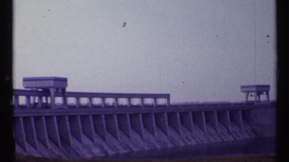 1967 Toronto frame of the dam's long concrete face, with segmented supports and small structures along the top.