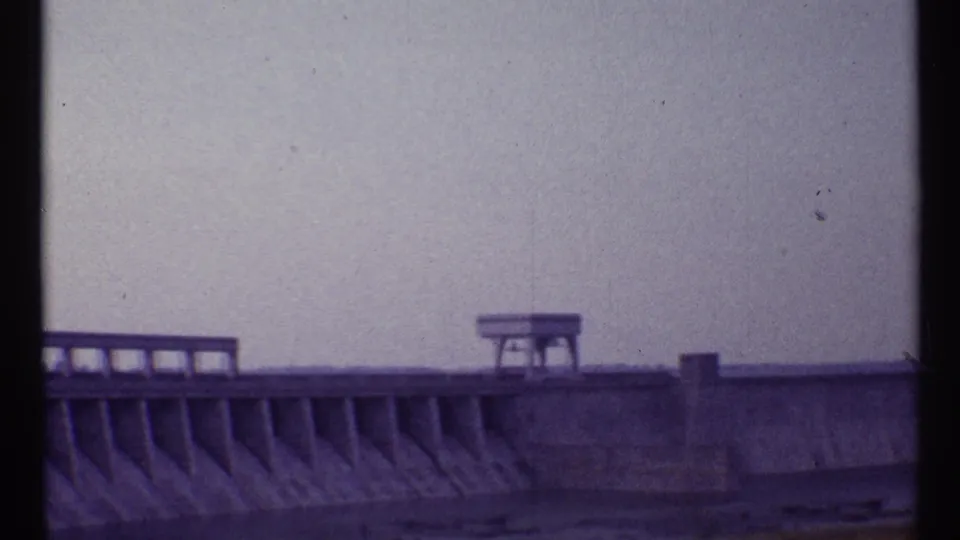 1967 Toronto frame with a large concrete structure, railings, and a small platform seen through 8mm film grain.