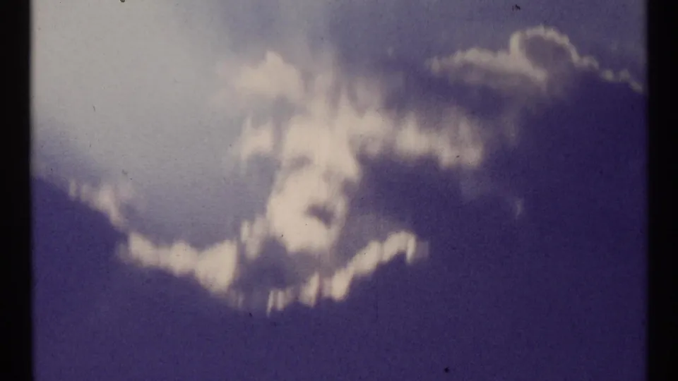 1967 Toronto home-movie frame with hazy clouds, strong blue cast, soft focus, and visible film grain.