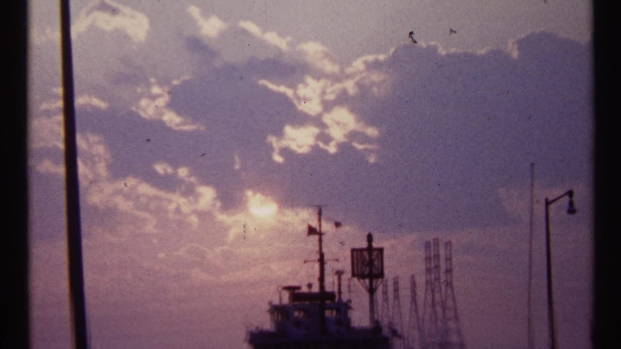 Sun breaking through clouds above a silhouetted harbor vessel and dockside structures.
