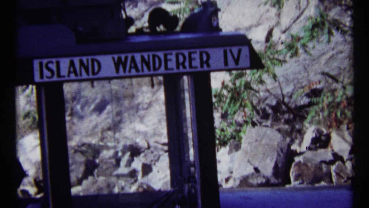 Island Wanderer IV sign over a boat window beside rocks and trees.