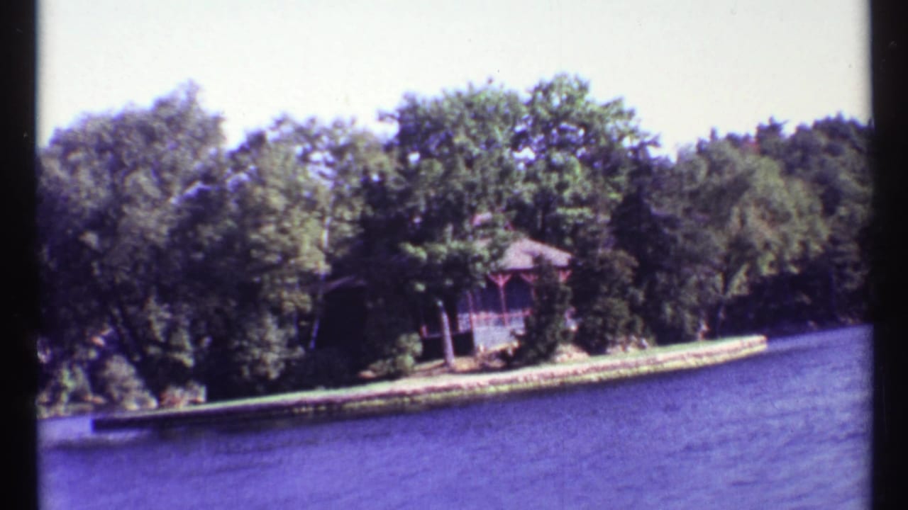 Boat-view shoreline with trees, water, and a small wooden gazebo-like structure.