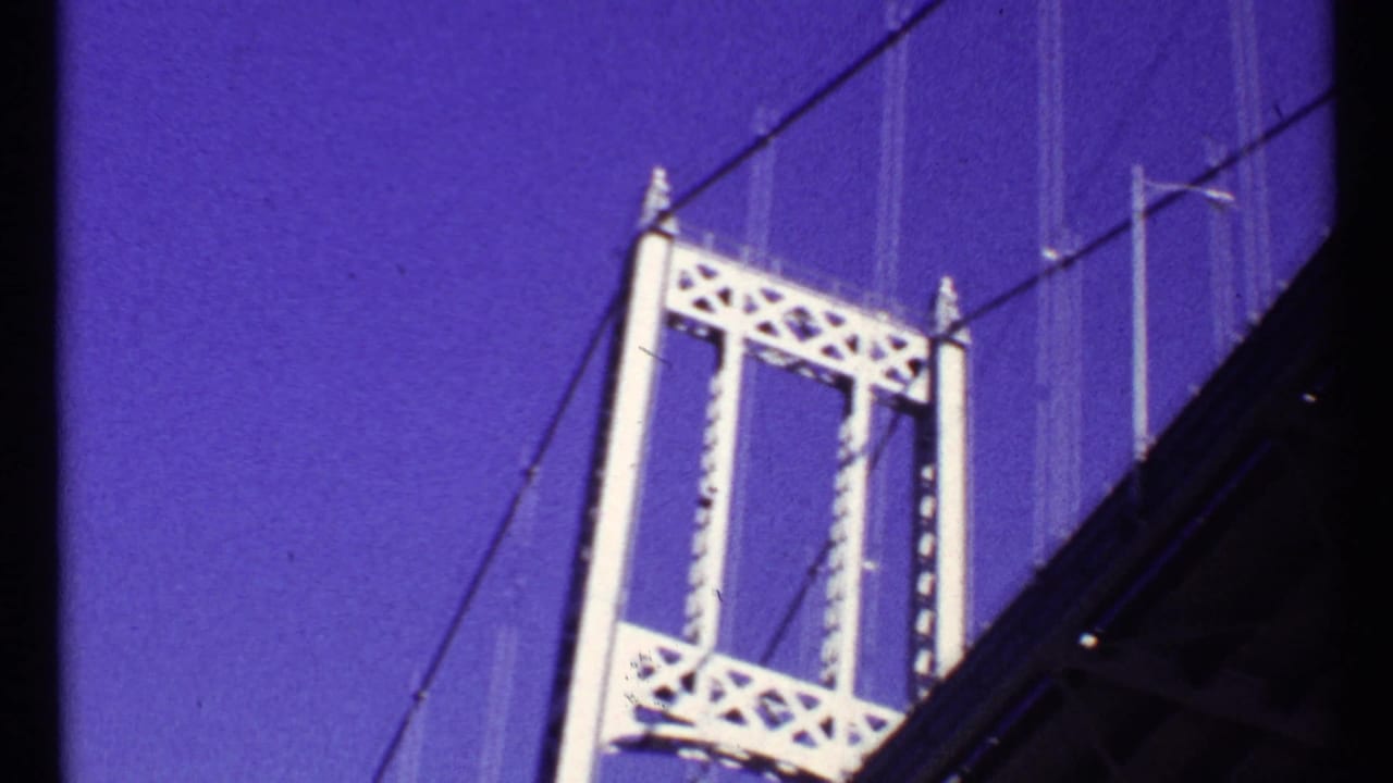 Low-angle view of a white suspension bridge tower against a deep blue-purple sky.