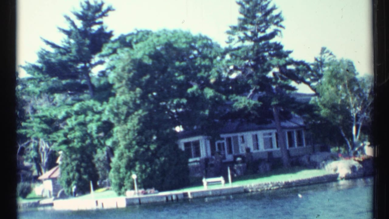 Waterfront house and dock area framed by dense trees along the shoreline.