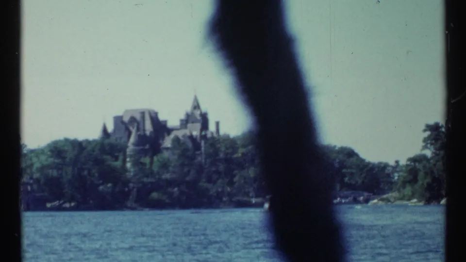 1967 Toronto waterfront view toward a distant castle-like building across the river, with a dark out-of-focus obstruction in front.