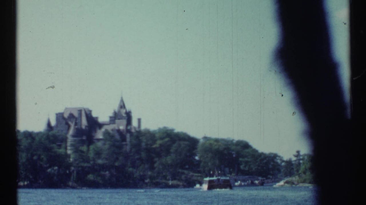Distant castle-like mansion above trees across lake water with a small boat near shore.