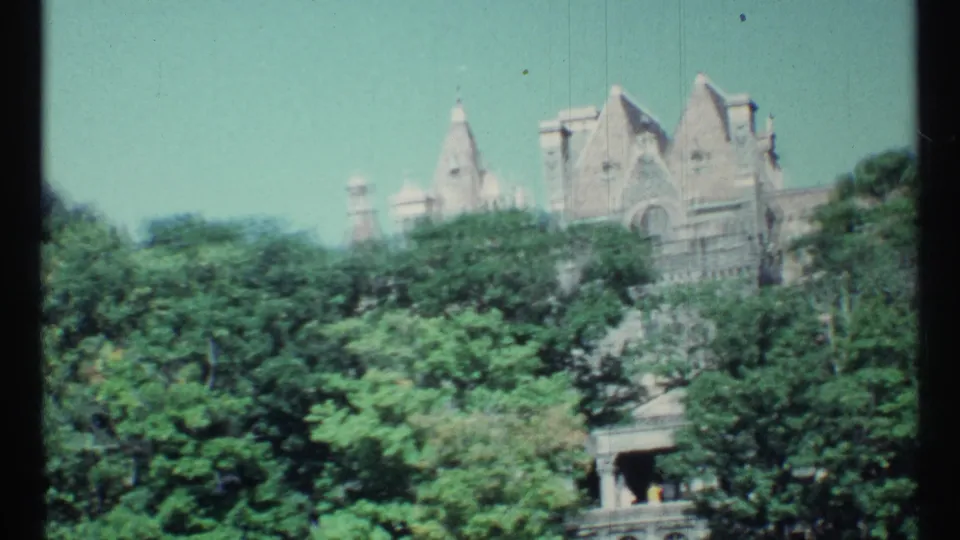 1967 Toronto frame showing a castle-like stone roofline above trees, with a small structure visible below the foliage.