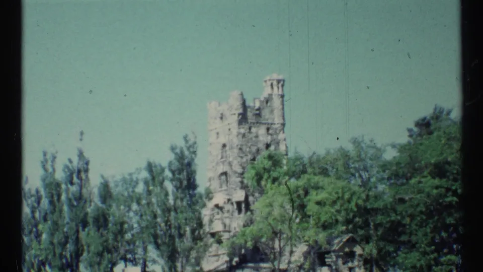 A 1967 8mm Toronto frame shows a castle-like stone tower above trees, with a small roofline near the lower right.
