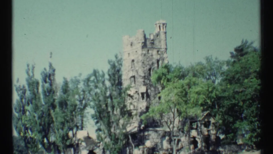 Final 1967 Toronto home-movie frame holding on the stone tower, leafy trees, and a small structure near the base.
