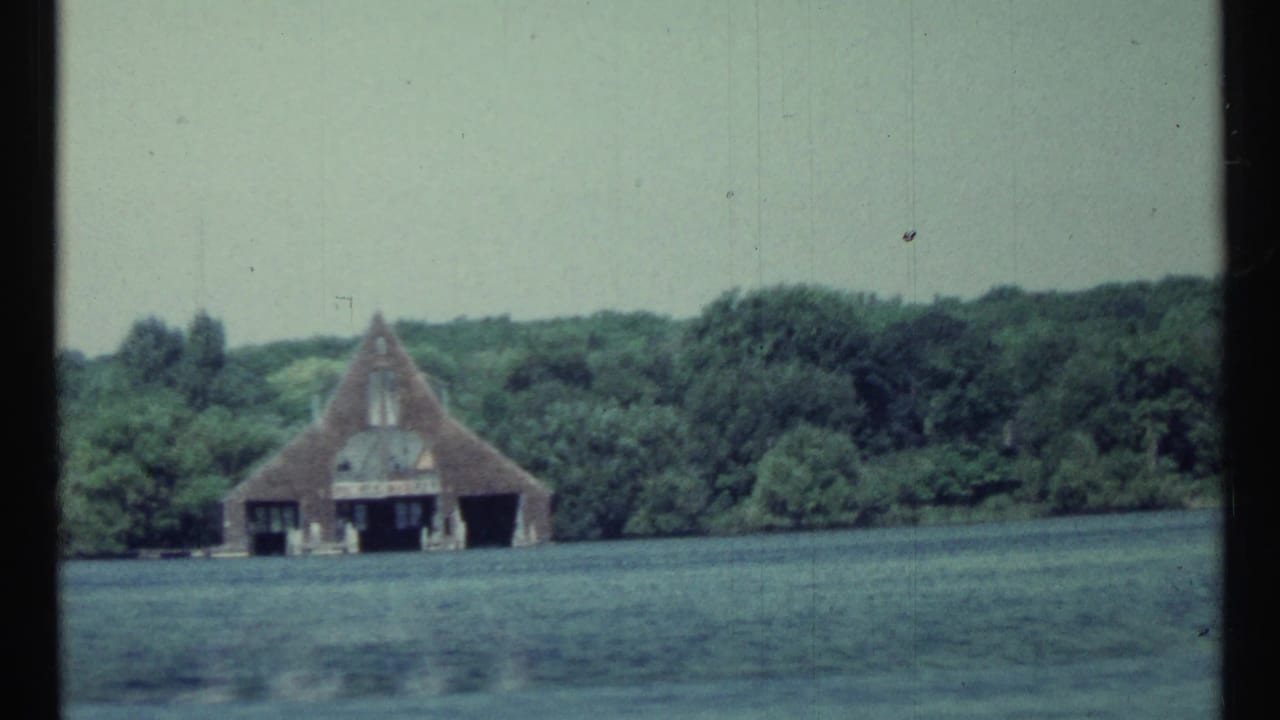 Distant boathouse and tower-like structure across rippling lake water.