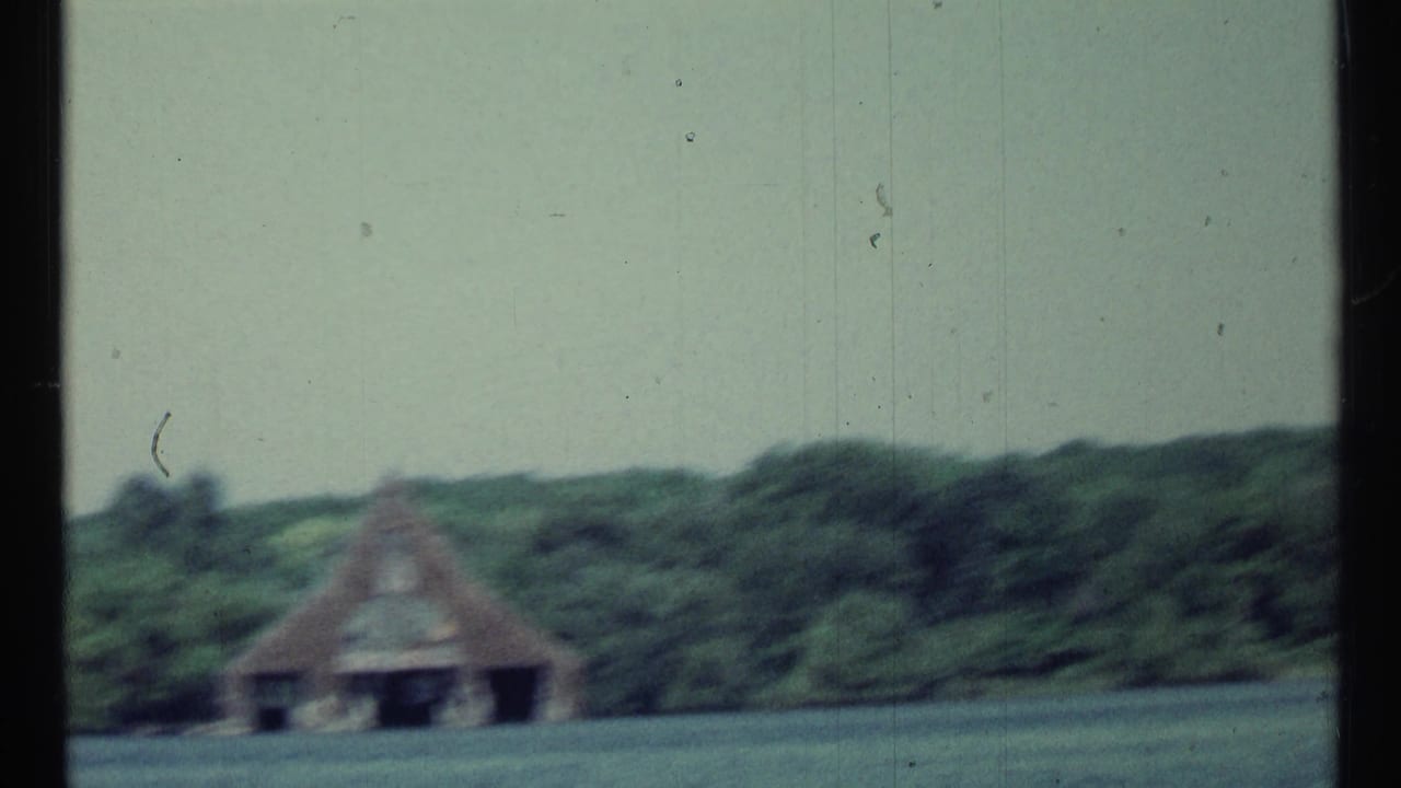 Soft 1967 Toronto lake view with a boathouse and trees seen from across the water during a pan.