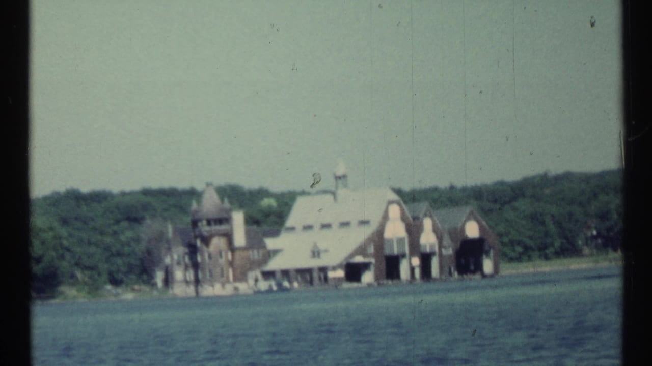 Large lakeside buildings with arched openings and trees behind them.
