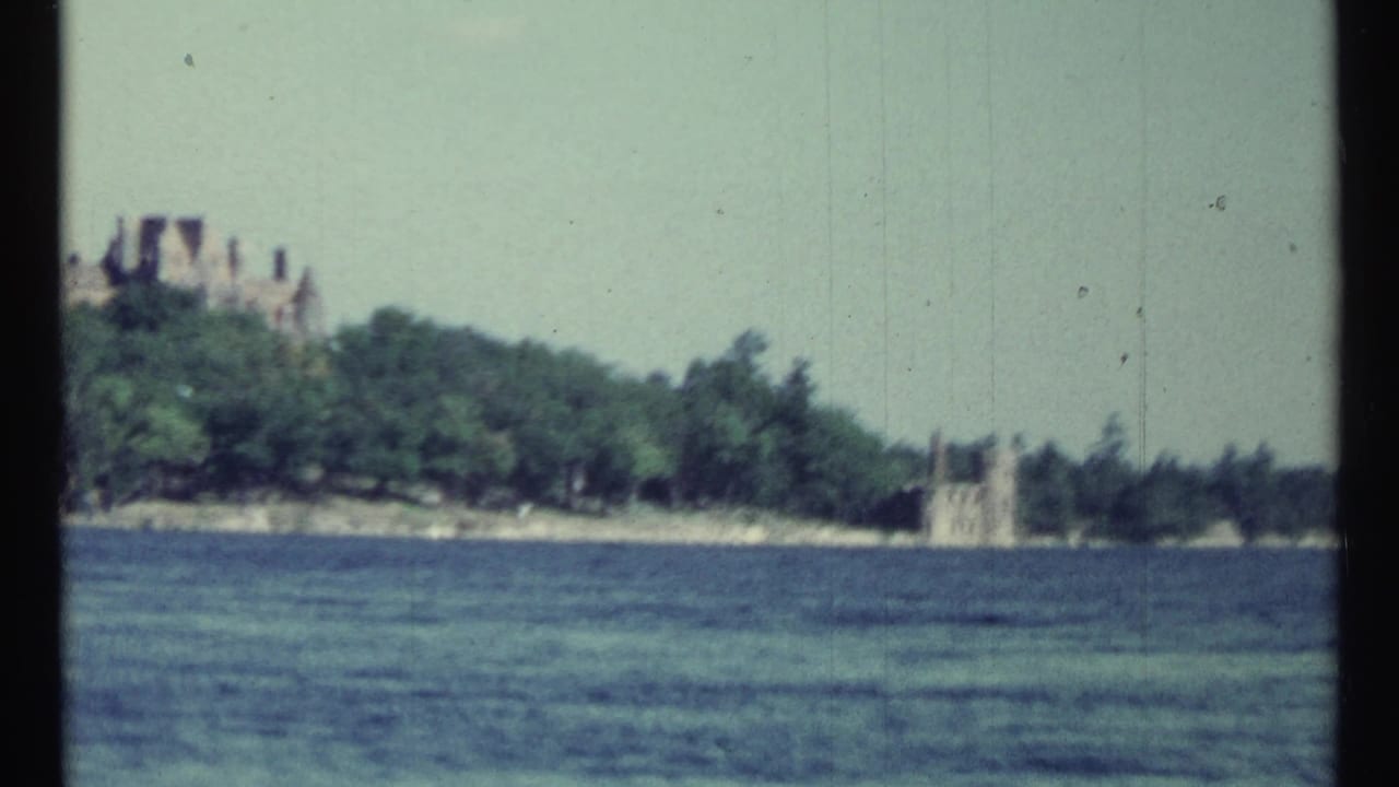 Wide lake view with distant estate buildings along a wooded shore.
