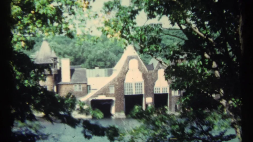 Closer 1967 Toronto view of a castle-like estate facade with gables, chimneys, arched openings, and foreground foliage.