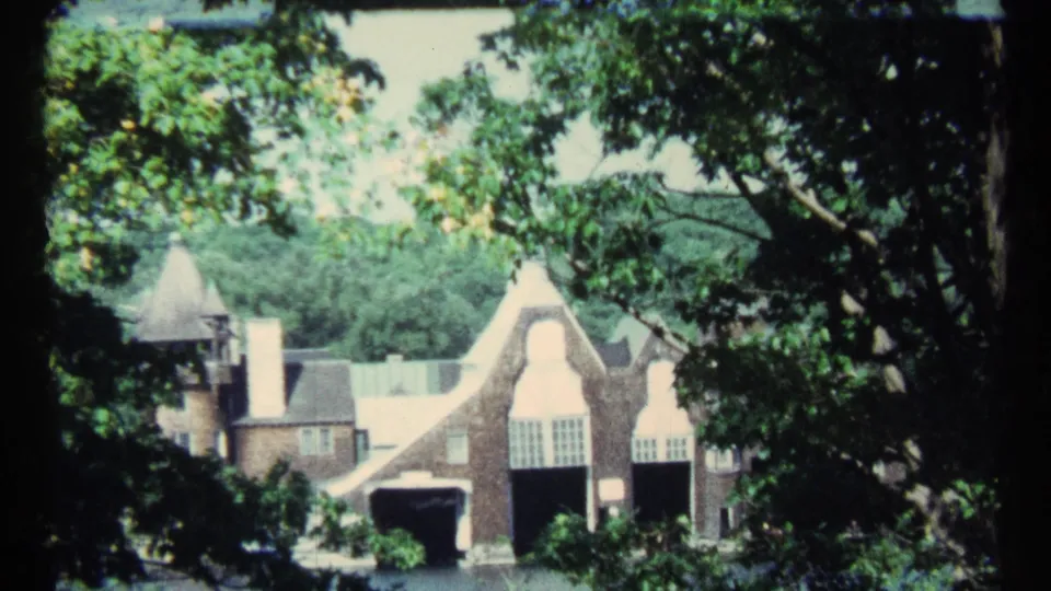 1967 Toronto home-movie view of a substantial brick residence framed by shaded branches and bright leaves.