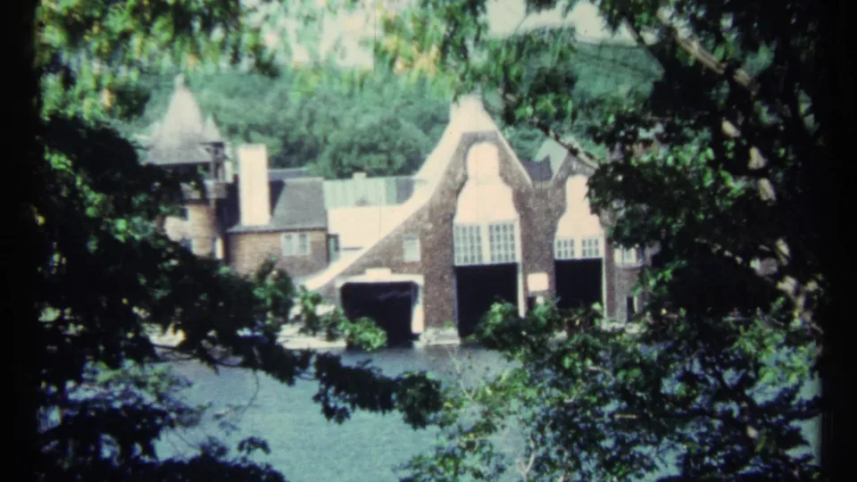 1967 Toronto frame showing the brick house partly screened by trees, with water visible along the lower foreground.