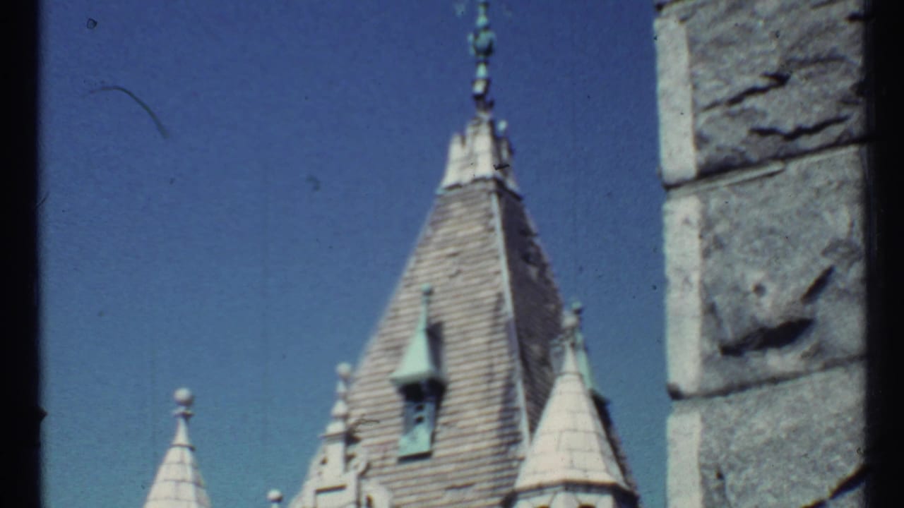 1967 8mm frame showing a pointed steeple, smaller spires, and rough stone wall edge, with the Toronto location supported by clip metadata.