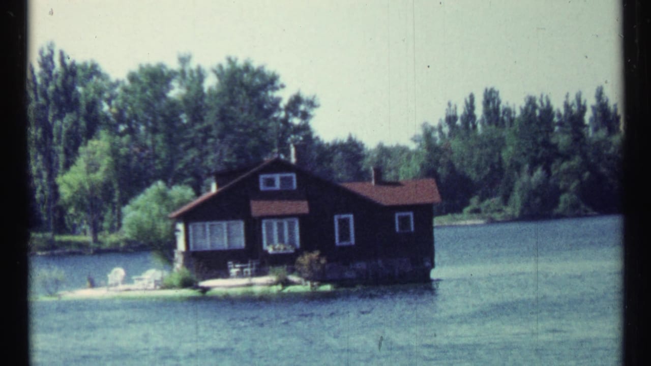 Cabin on a small island seen across rippling lake water.