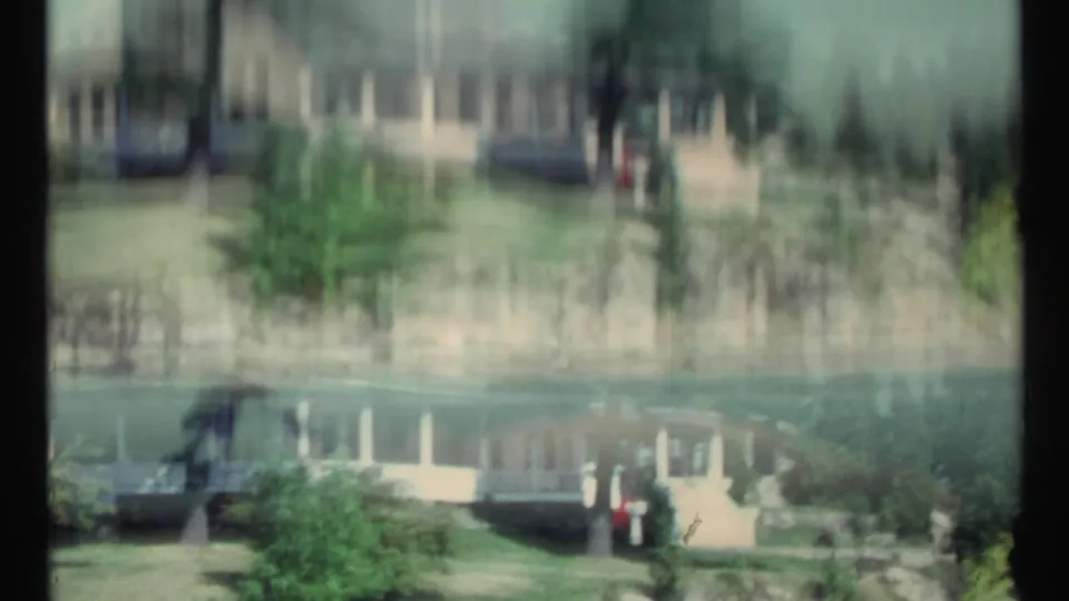 Soft 1967 8mm frame of the white lakeside house near Toronto, with water reflection and heavy motion blur.