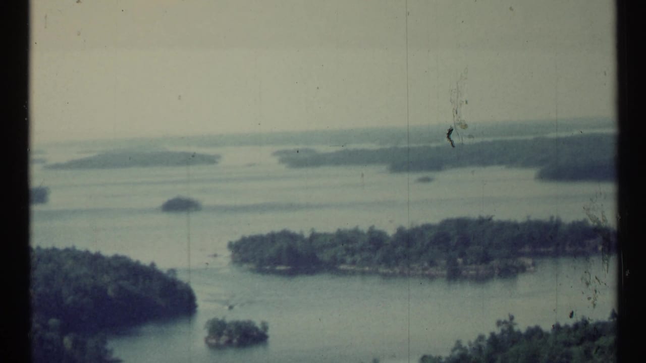 Aerial view over lake channels, wooded islands, and distant shoreline.