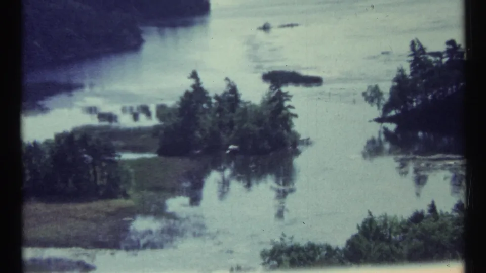 Toronto-area 8mm frame from 1967 showing flooded lowland, wooded islands, and muted blue-green home-movie color.