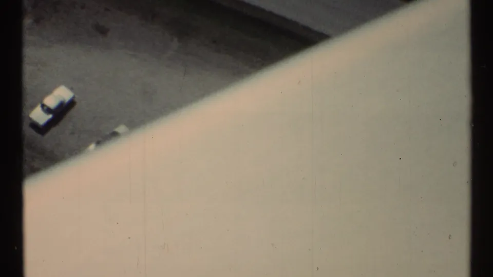 1967 Toronto home-movie frame showing a parking lot below, with small cars and a pale curved viewing-station edge dominating the foreground.