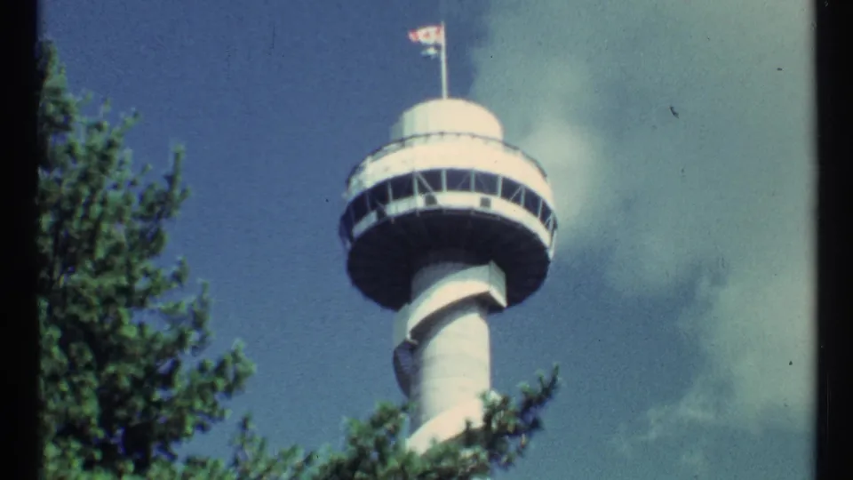 Final 8mm frame of the tower and observation deck seen above trees, with flags visible near the top.
