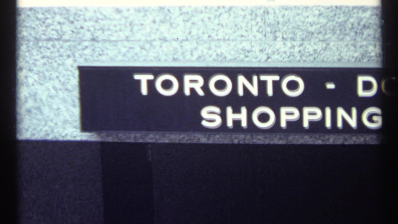 1967 Toronto home-movie title card with partial text reading Toronto and shopping, seen through a dark film edge.