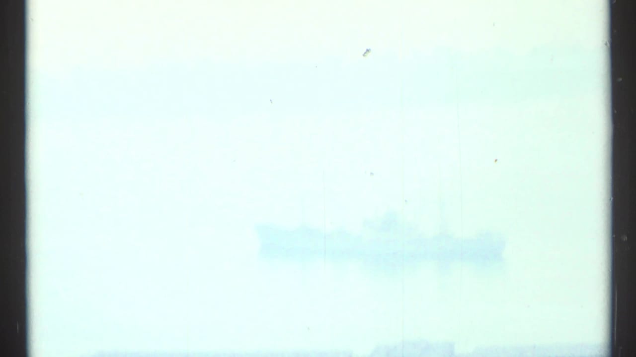 Pale hazy sky and water with dark vertical film edge at left.