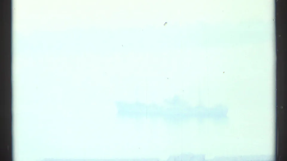Soft, overexposed 8mm frame of pale sky and water near Toronto, divided by a dark film edge.