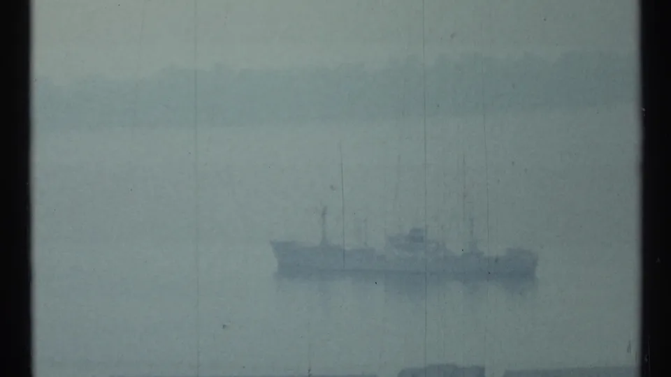 Distant naval-looking vessel on hazy Toronto harbor water, rendered in soft blue-grey 8mm color.