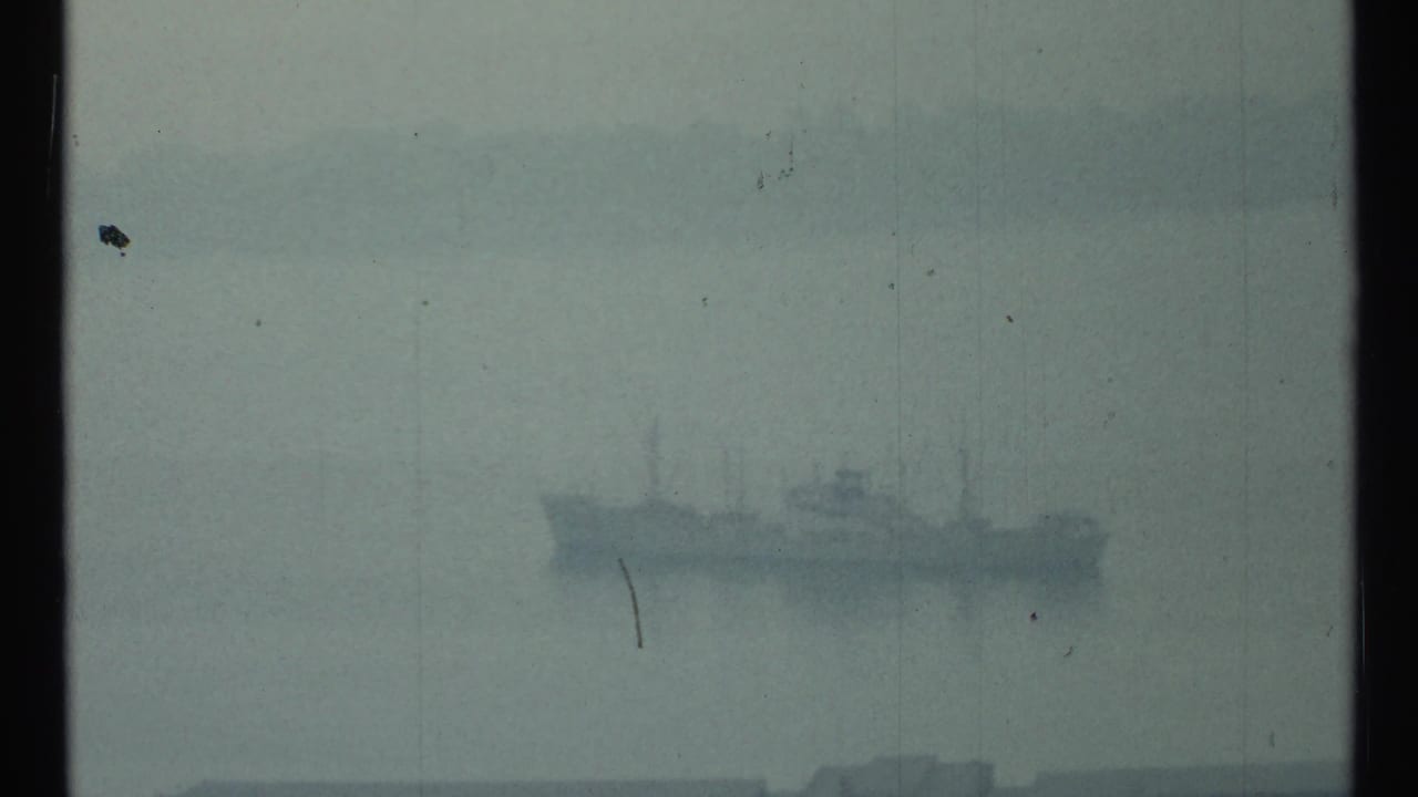1967 Toronto home-movie frame showing a distant ship barely visible through fog over the harbor.