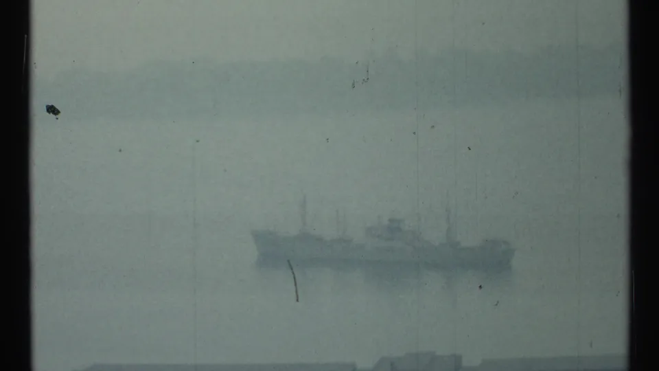 1967 Toronto home-movie frame showing a distant ship barely visible through fog over the harbor.