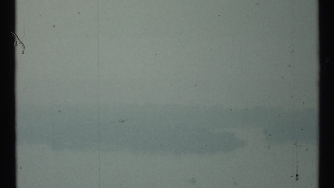 Hazy waterfront view with faint skyline shapes and film gate edge.