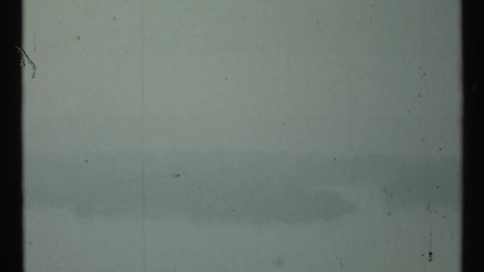 Fog-softened Toronto waterfront view on 8mm film, with indistinct skyline forms beyond the water.